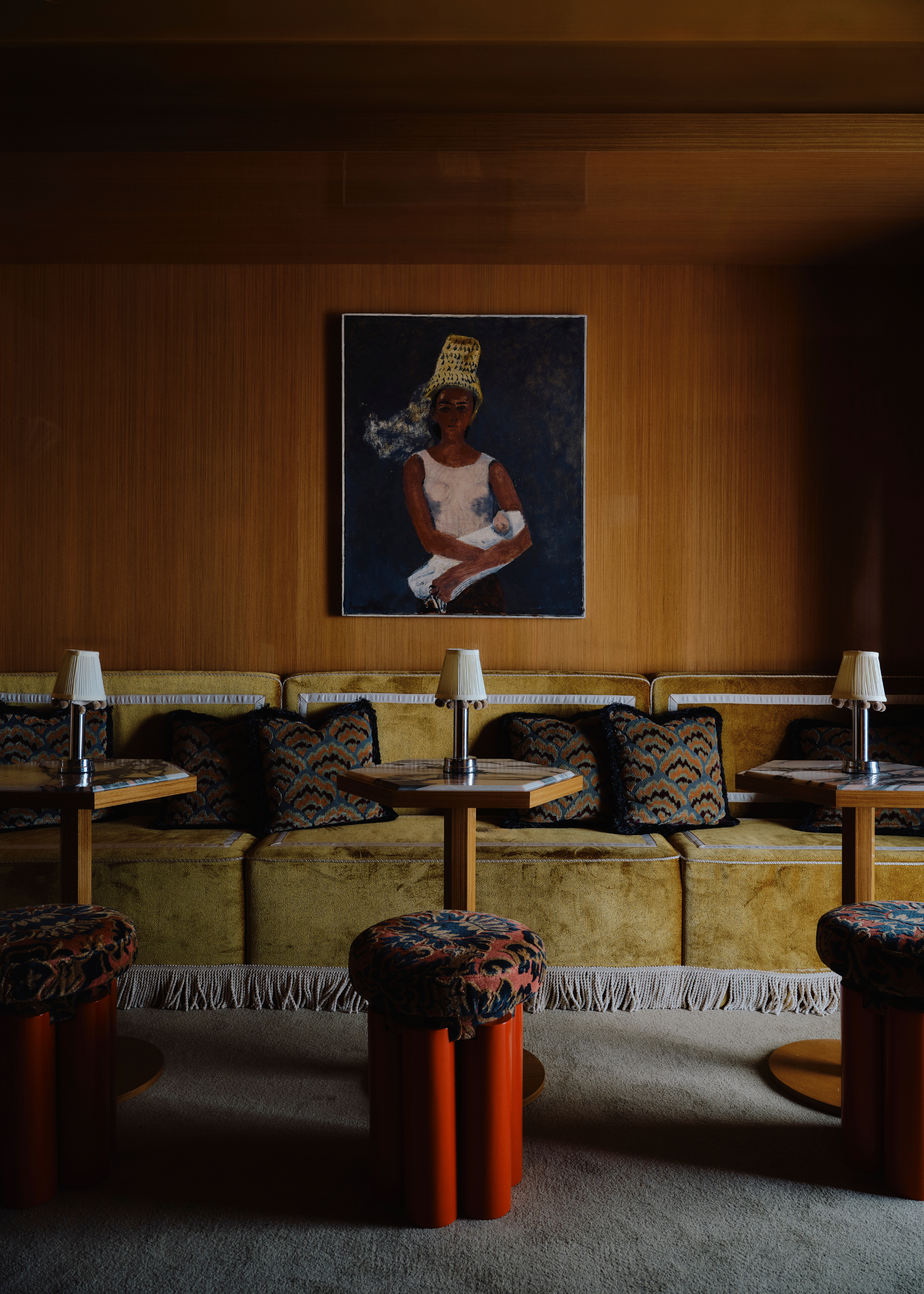 wood clad walls with low green velvet fringed sofas and small table