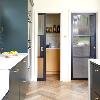 pocket door leading to a pantry in a kitchen extension with dark blue kitchen cabinetry