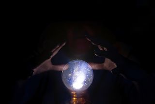 A unseen person's hands hover near a crystal ball