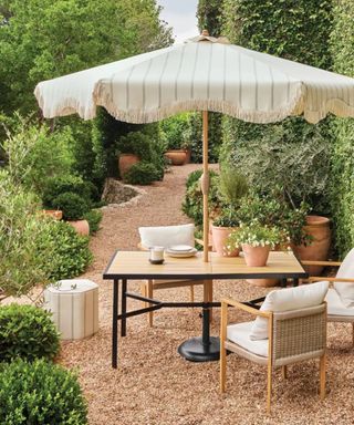 Garden with umbrella, wooden table and wooden outdoor chairs