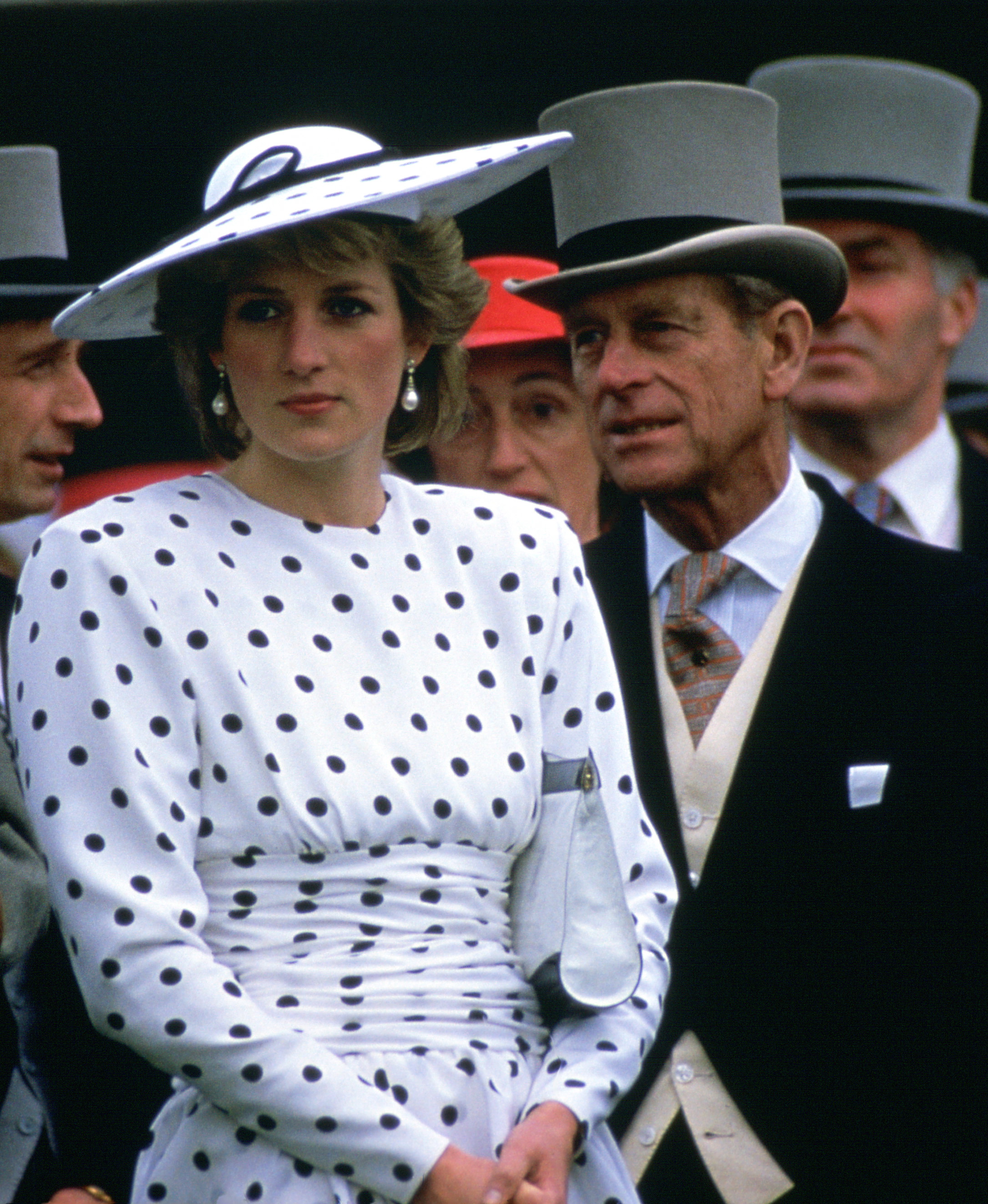 Princess Diana wearing a white dress with black polka dots standing in front of Prince Philip