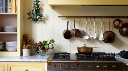 yellow kitchen with hanging rail and pot on stovetop