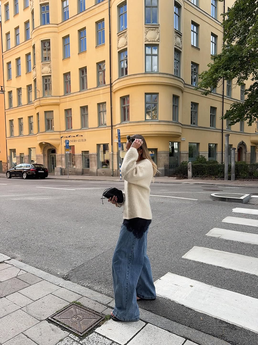 Woman wearing long, baggy jeans fall denim trend 2025.