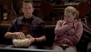 Lee enjoys his popcorn while watching TV with Lucy in Not Going Out