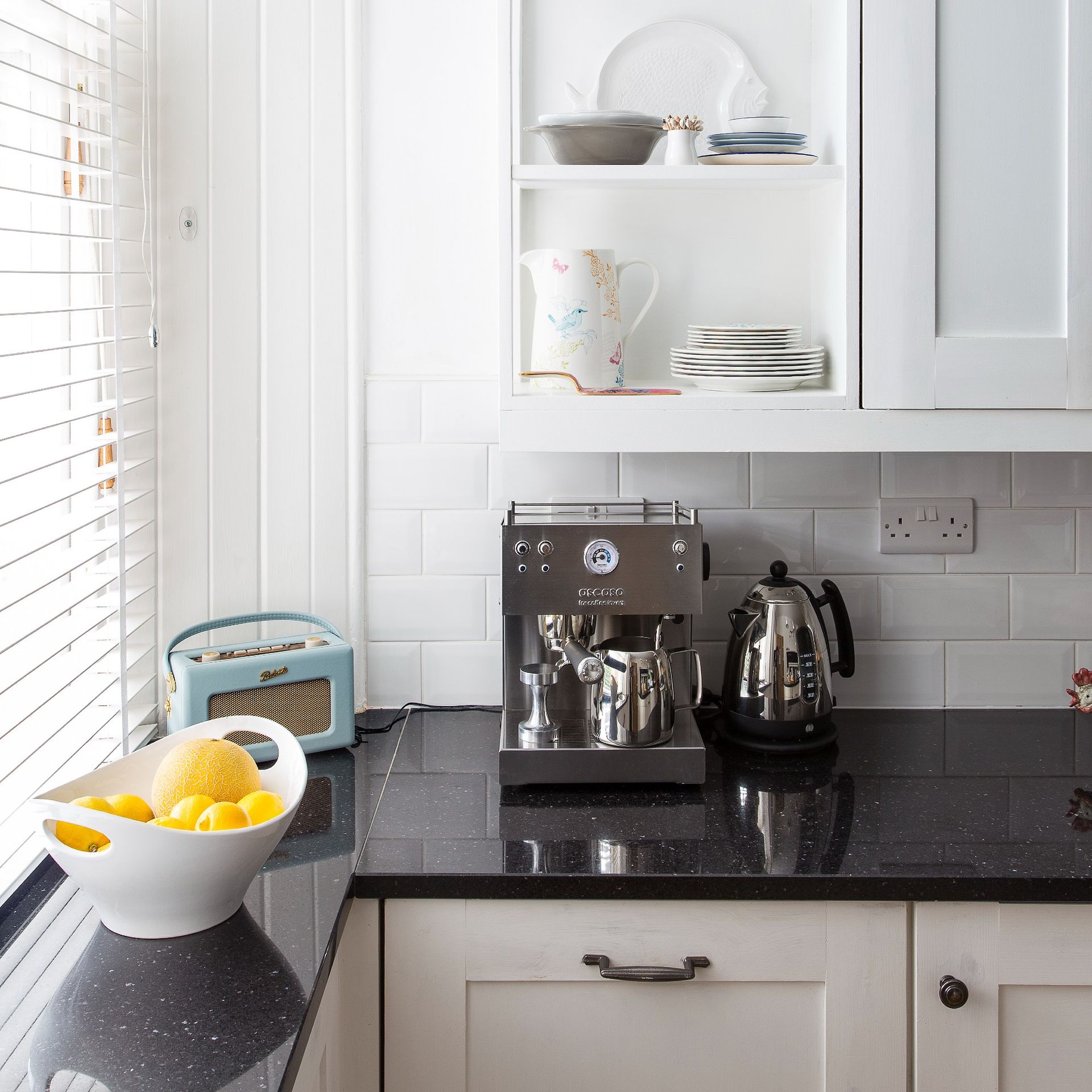 A white-tiled kitchen with a kettle and a coffee machine