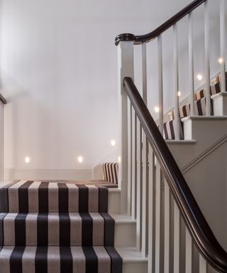 A brown stair railing with brown and grey staircase runner