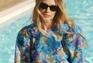 Woman wearing blue Adoore floral print minidress in front of pool.