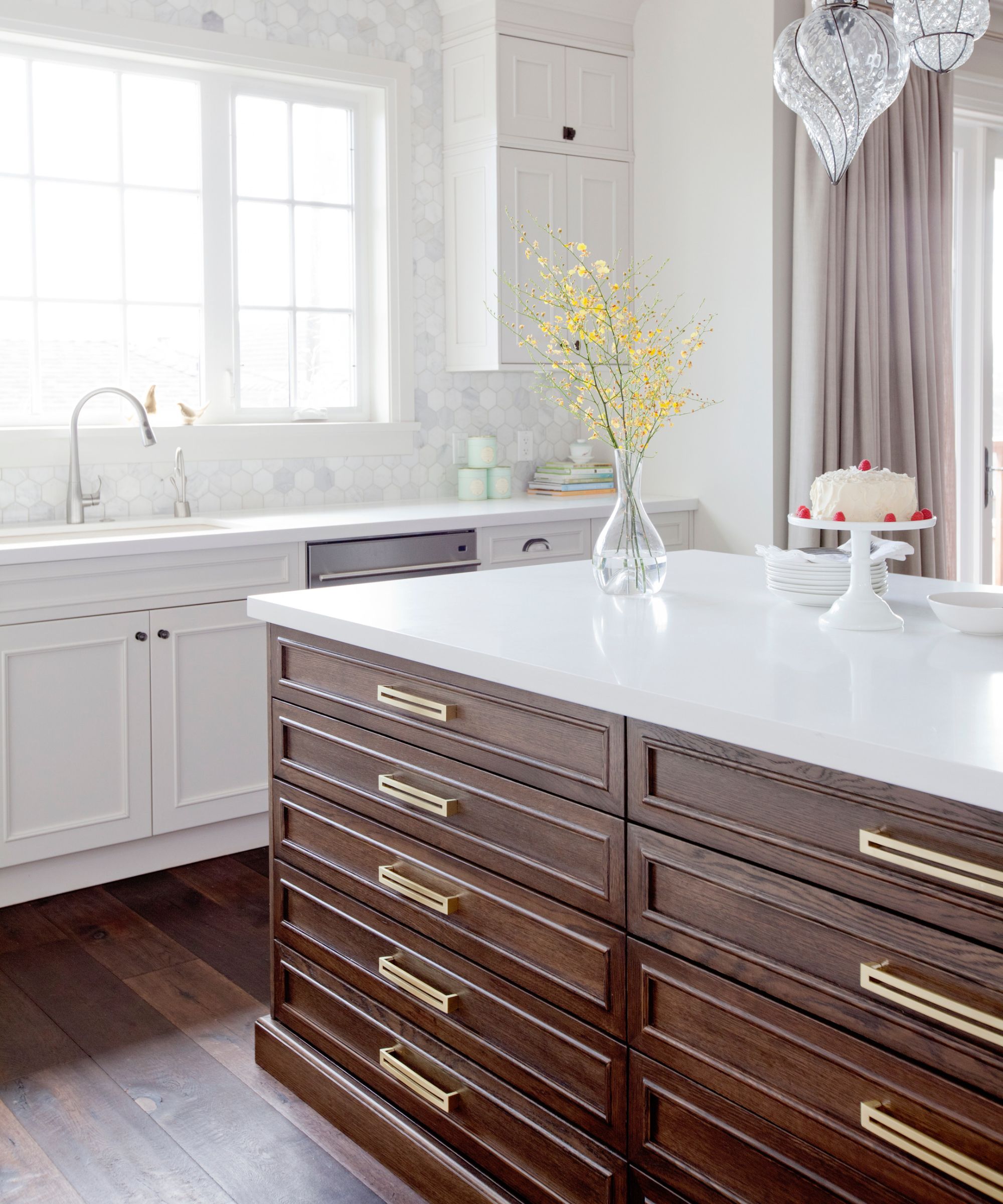 A 2015 kitchen with white cabinets, a dark wood island, and brass hardware