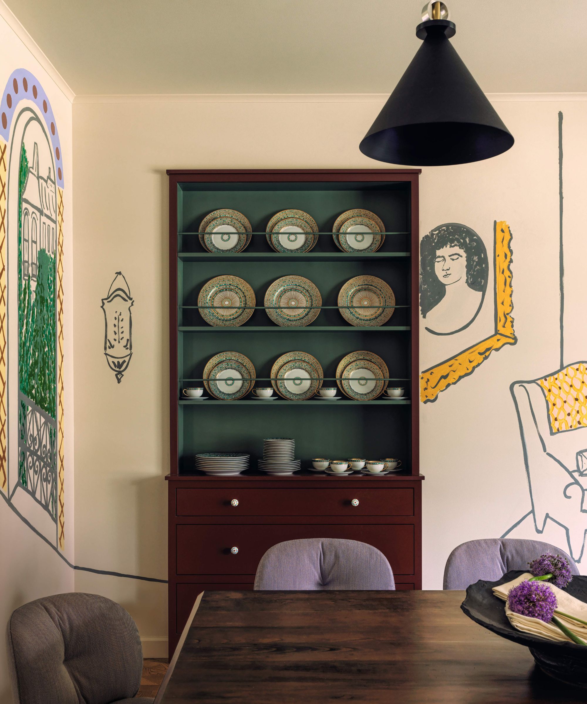 Dark wooden dresser in a dining room with hand painted murals