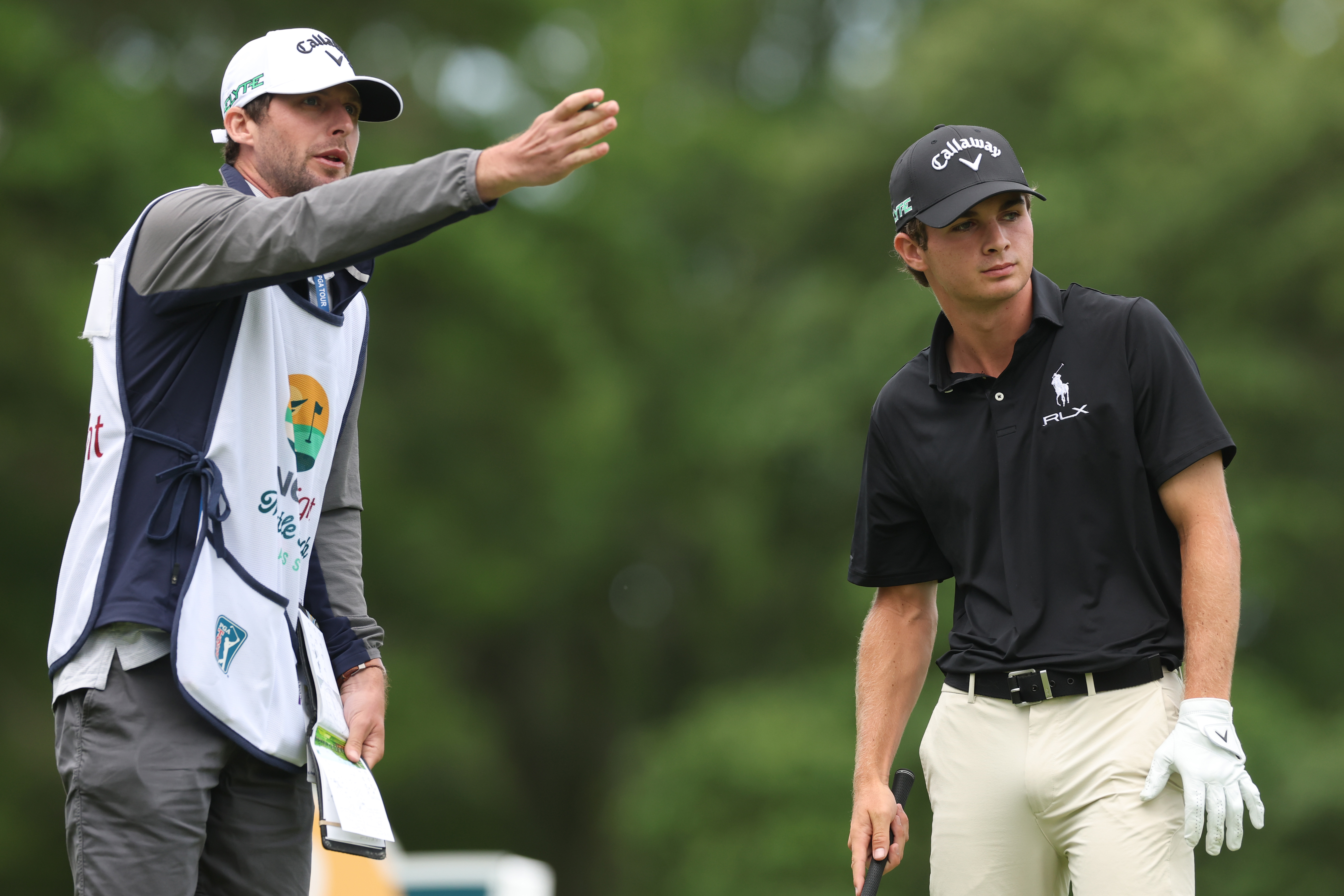 A caddie points forward while Jackson Byrd watches on