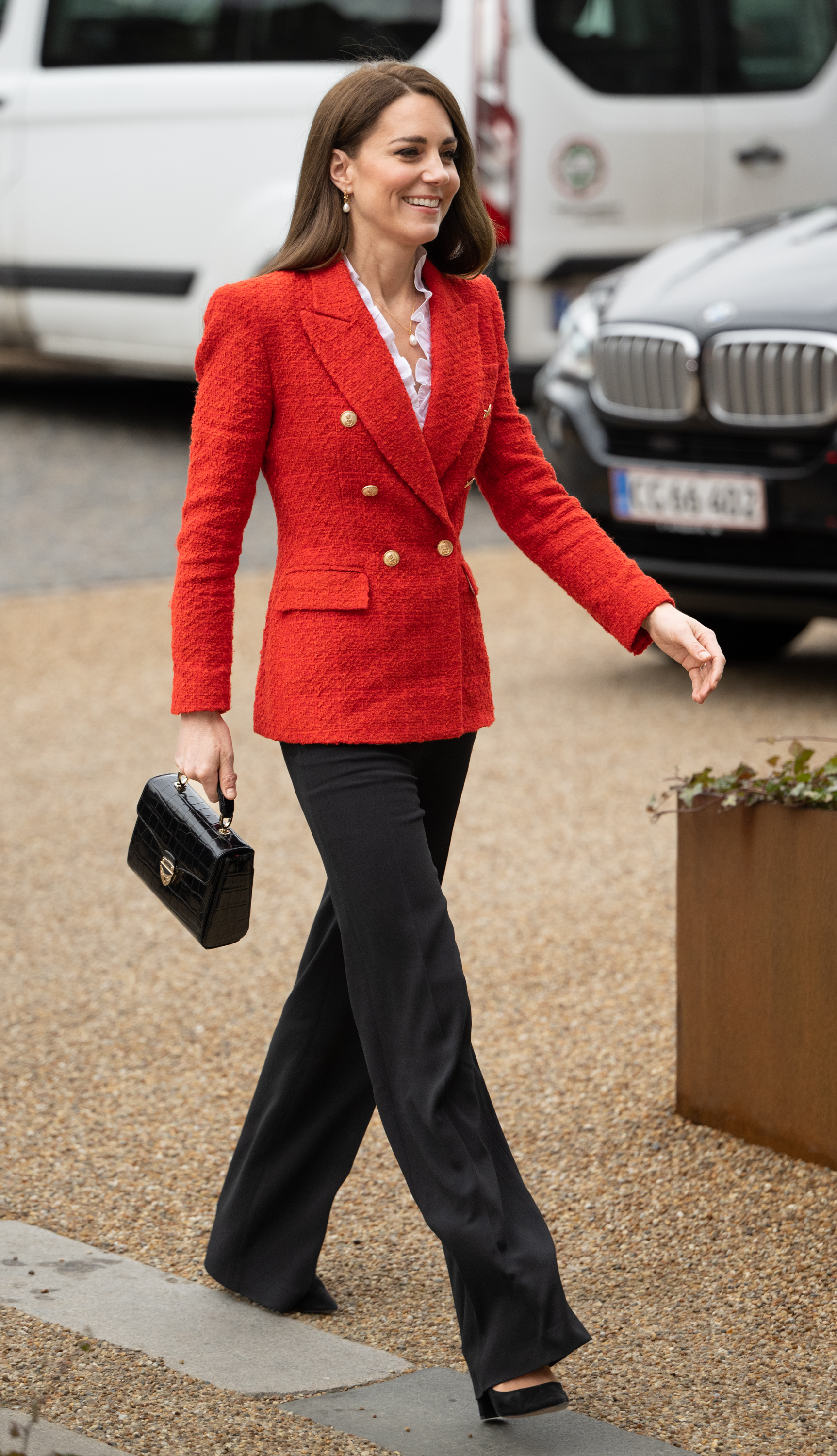 Princess Kate wearing a red blazer walking and swinging a black bag