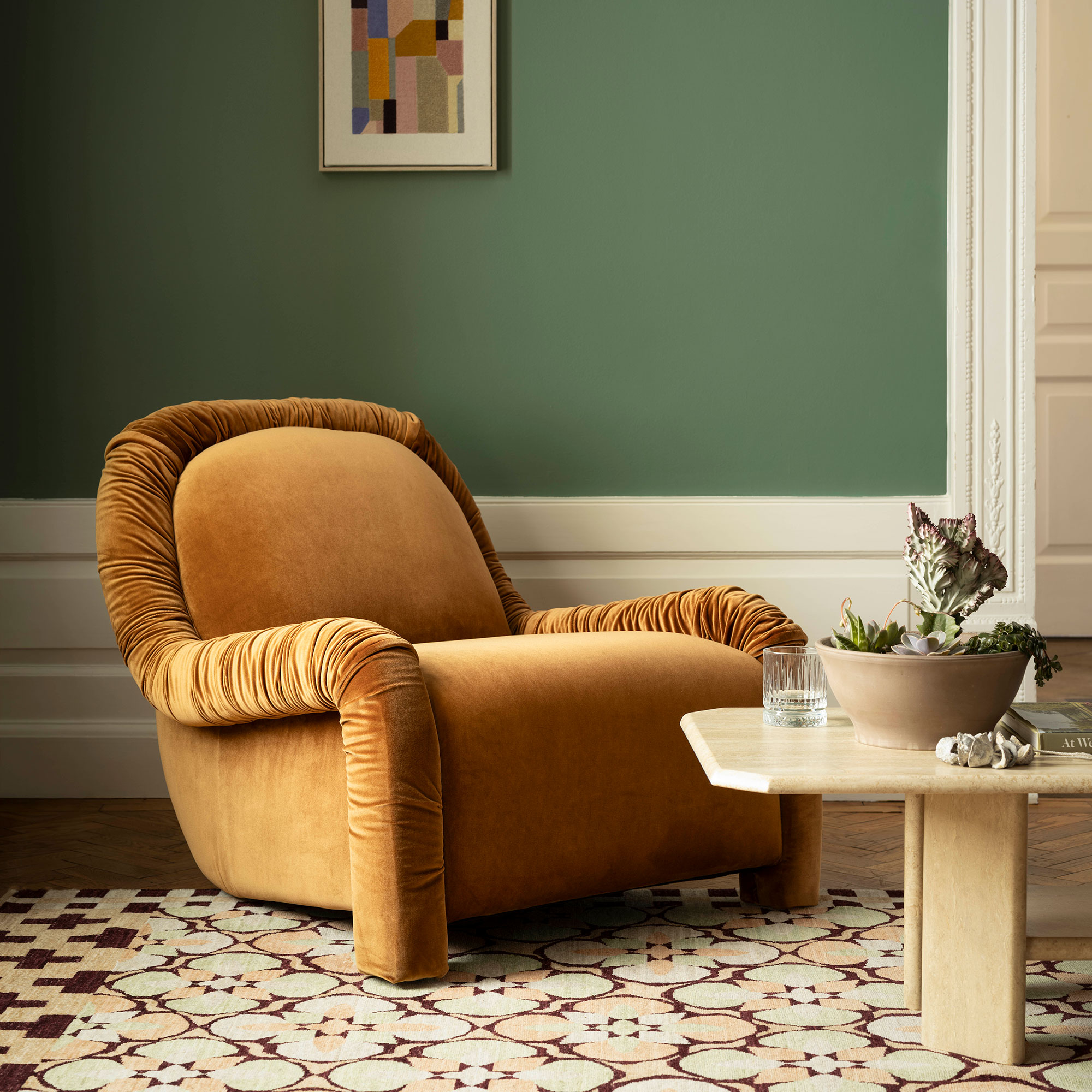 Living room wall painted in Benjamin Moore's Webster Green behind a velvet rust-coloured armchair