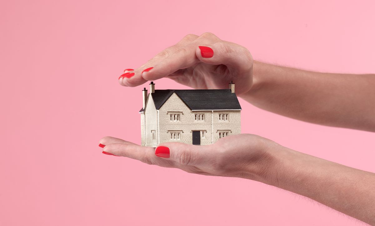 HELOC vs Home equity loan: A tiny house sitting in a person&#039;s palm in front of a pink wall