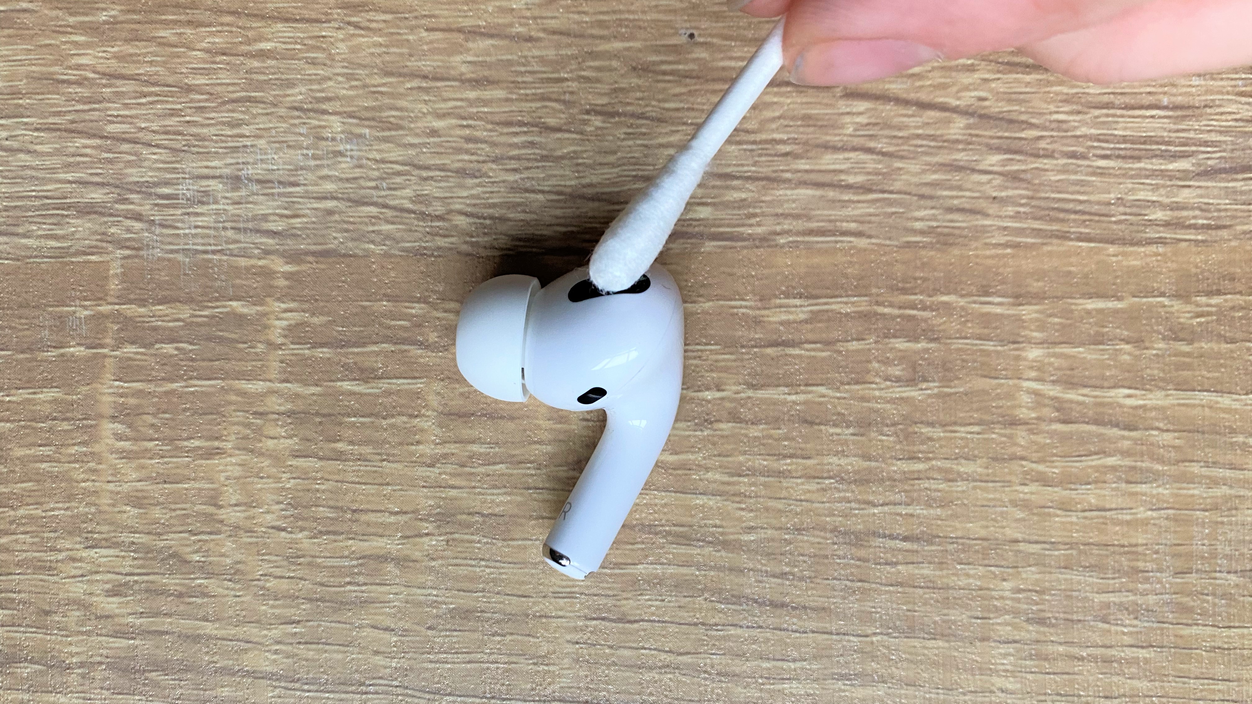 Using a cotton bud to clean the apple airpods pro