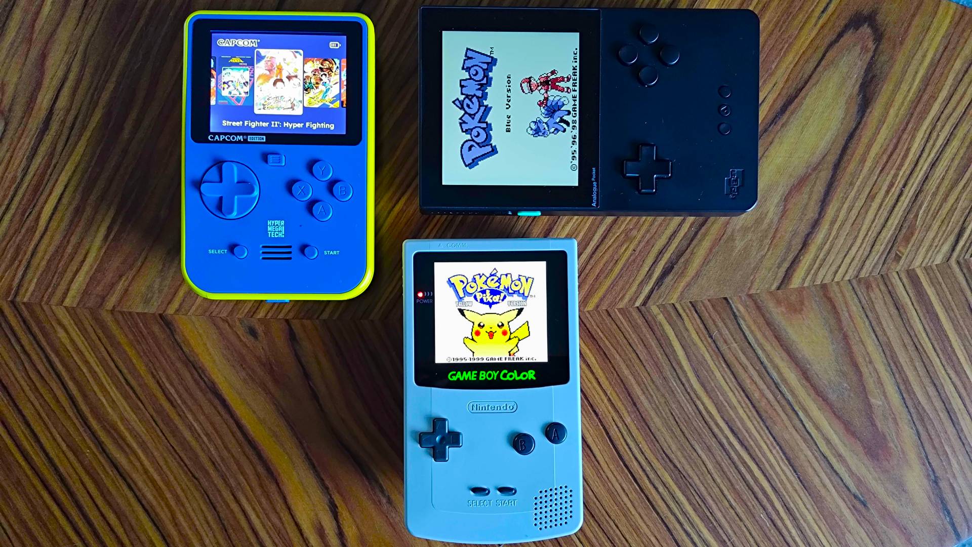 Super Pocket, Analogue Pocket, and Game Boy Color with AMOLED screen on woodgrain table.