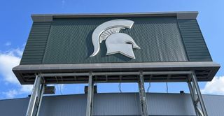 A massive board with the Michigan State Spartans logo on it with audio systems powered by Fulcrum Acoustic.