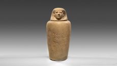 An ancient Egyptian clay vessel depicting a human.