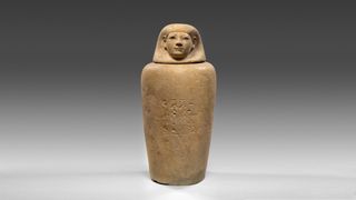 An ancient Egyptian clay vessel depicting a human.
