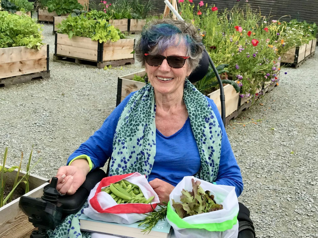 A smiling woman in a raised bed garden