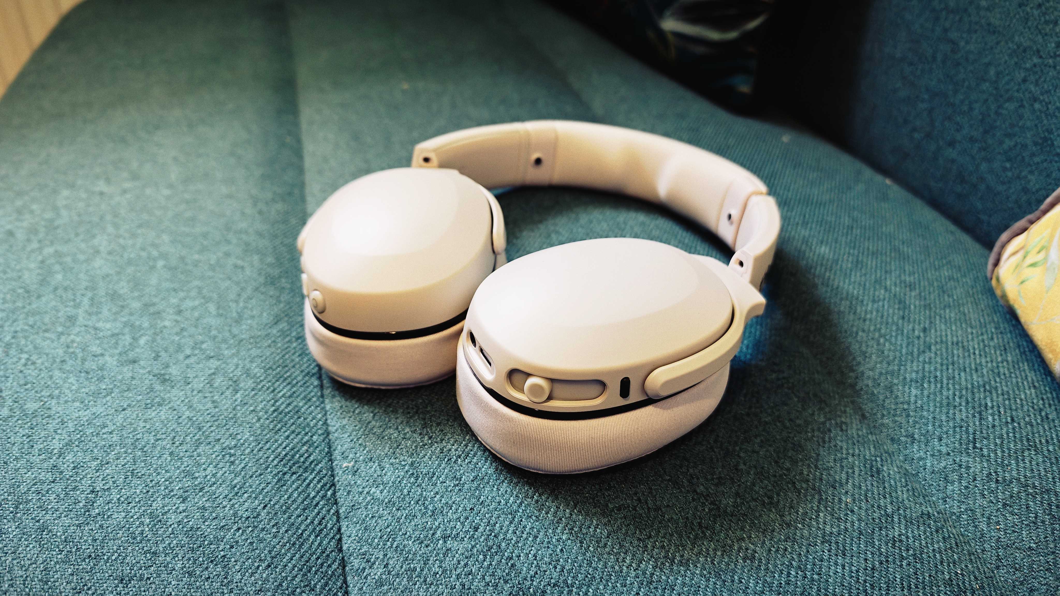 A white pair of Skullcandy Crusher 540 Active headphones on a green sofa