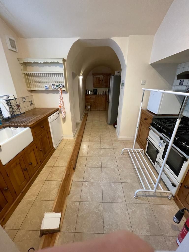 The wooden kitchen before the renovation with porcelain tiled floor and a belfast sink