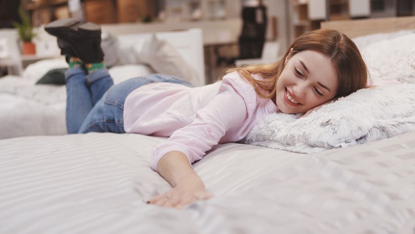 A woman with brown hair lies on her stomach on top of a mattress for front sleepers that she has chosen to buy