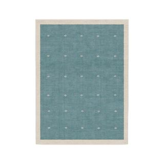 A rectangular teal blue rug with a beige border around it