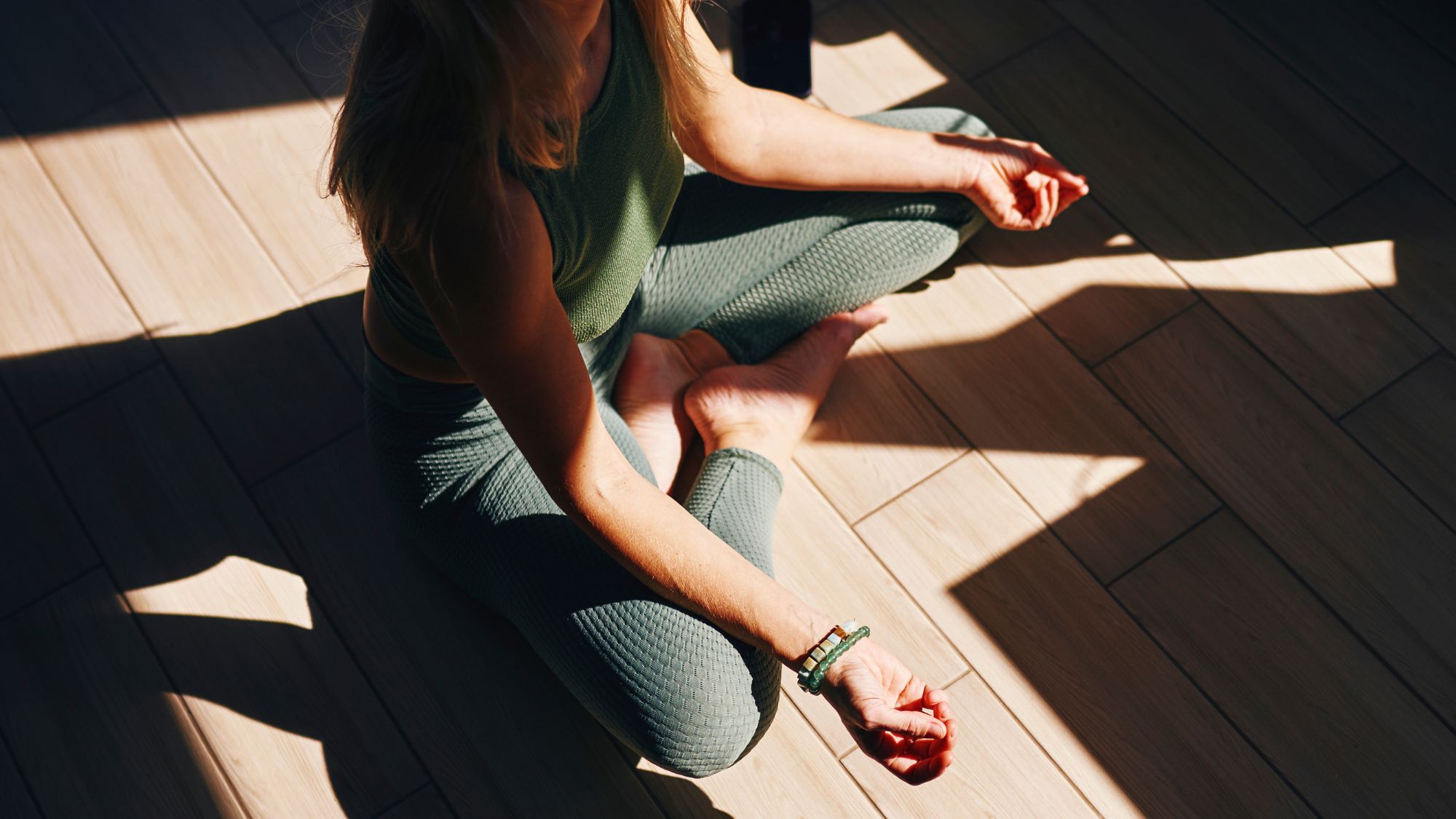 A woman meditating on the floor of a sunlit studio