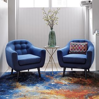 white wall with blue sofa chair and blue designed rug