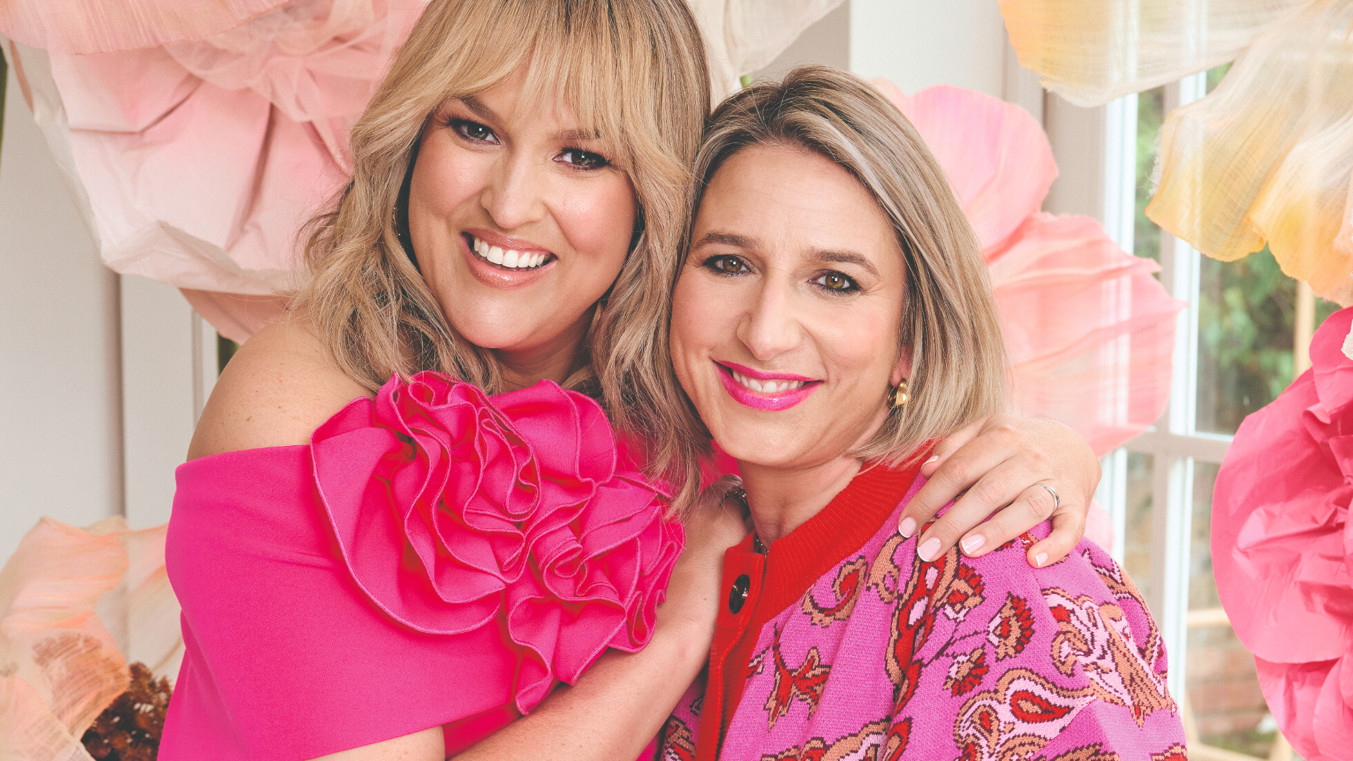 Sara Davies and Hannah Fernando wearing pink and smiling at the camera 