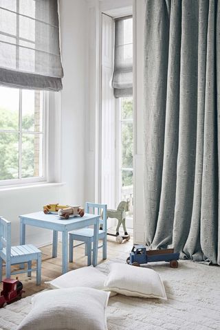 how to design a kid's room The corner of a nursery with big windows and a collection of small blue chairs and airy blue curtains and blinds
