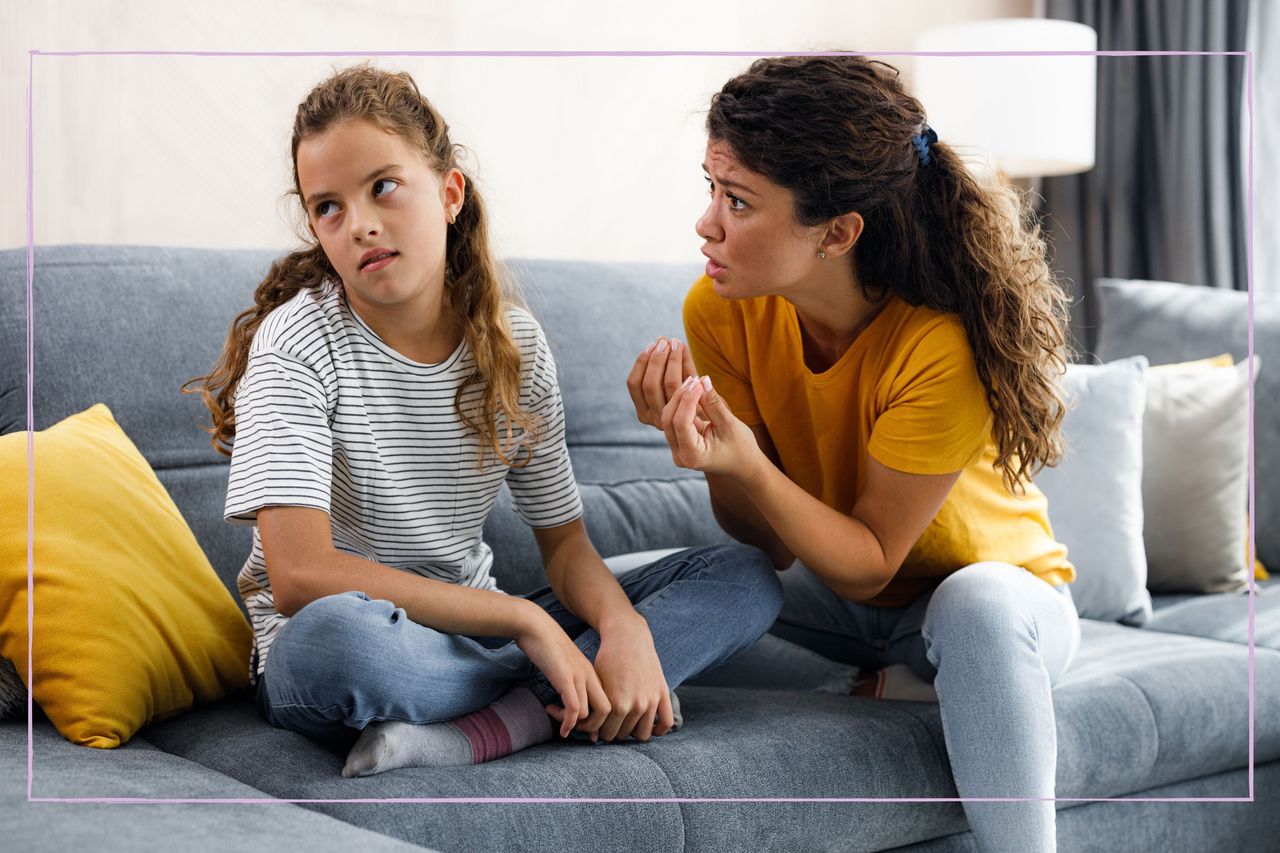 A young girl ignoring her mother while sat on a sofa