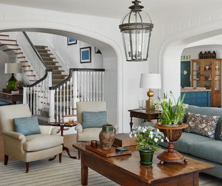 living room with dark coffee table staircase white walls blue sofas