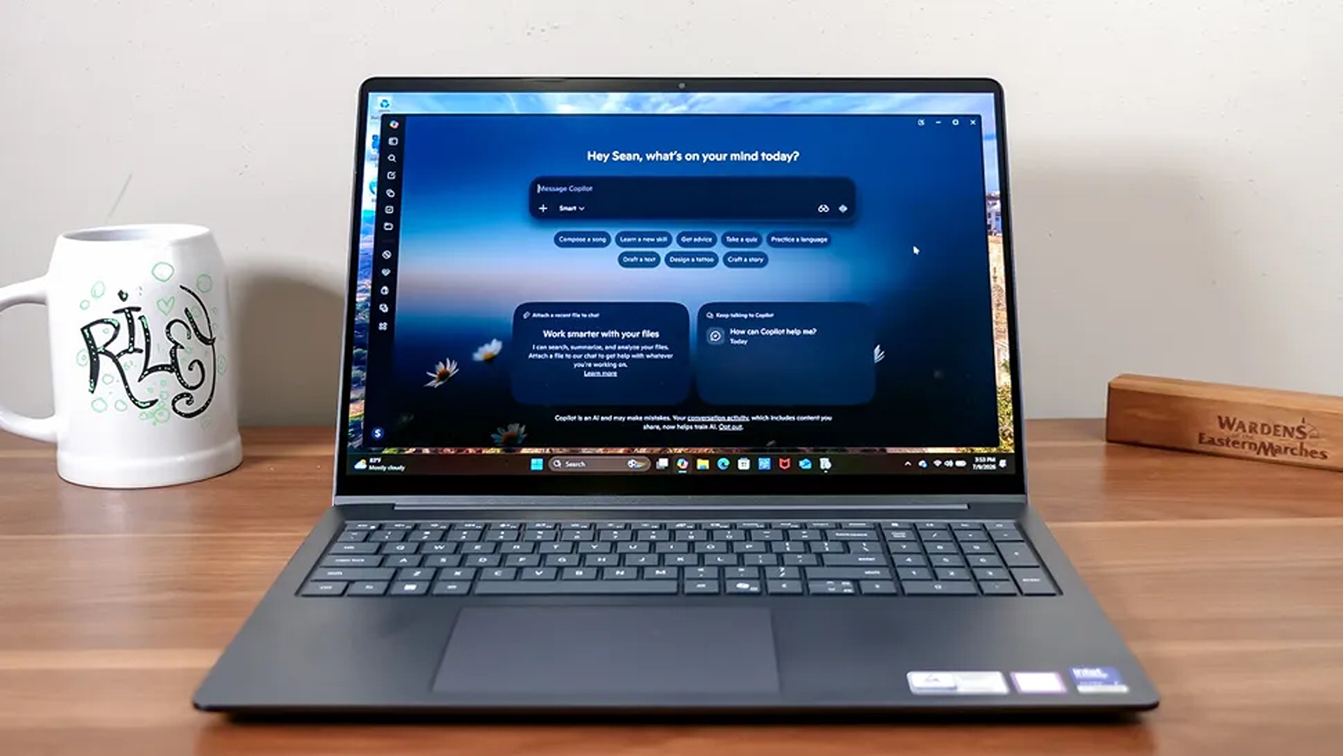 A laptop on a wooden desk displays a dark blue AI chat interface, with a white illustrated mug and wooden nameplate beside it in a calm home-office setting.