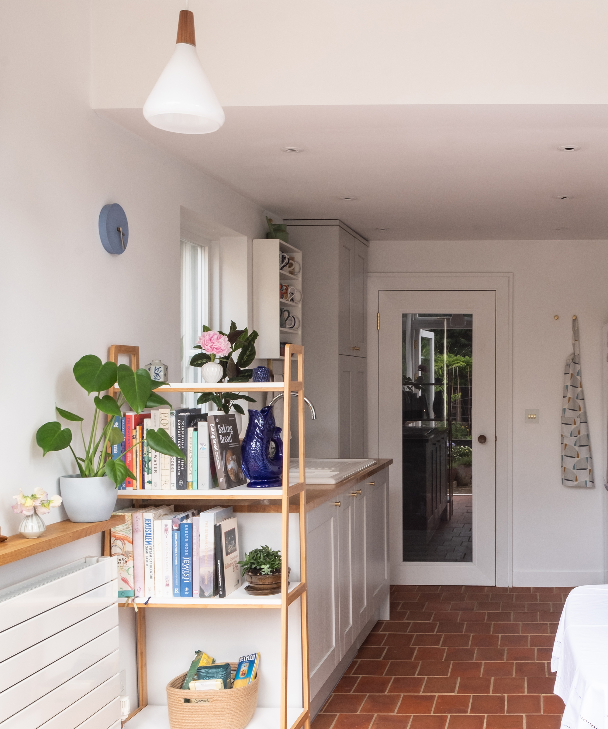 Terracotta flooring in a small kitchen with white cabinets