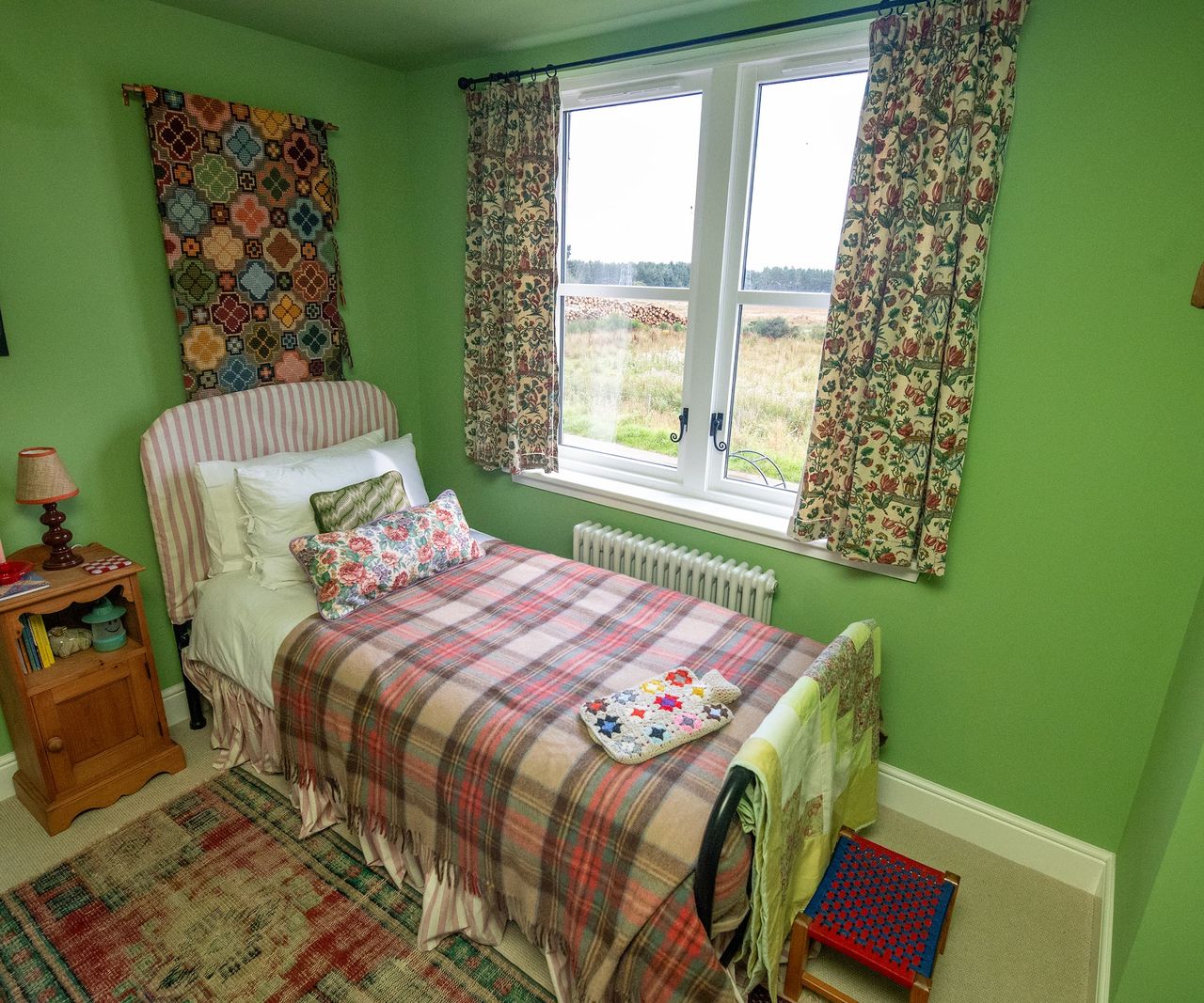 A mint-green walled bedroom with tartan bed covers