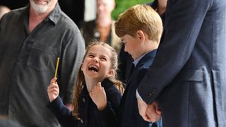 Princess Charlotte of Cambridge laughs as she conducts a band next to her brother Prince George of Cambridge during a visit to Cardiff Castle on June 04, 2022 in Cardiff, Wales