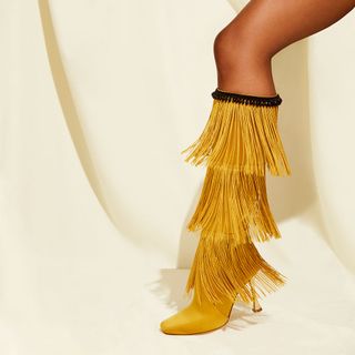 Below the knee boot in mustard yellow with tassels.