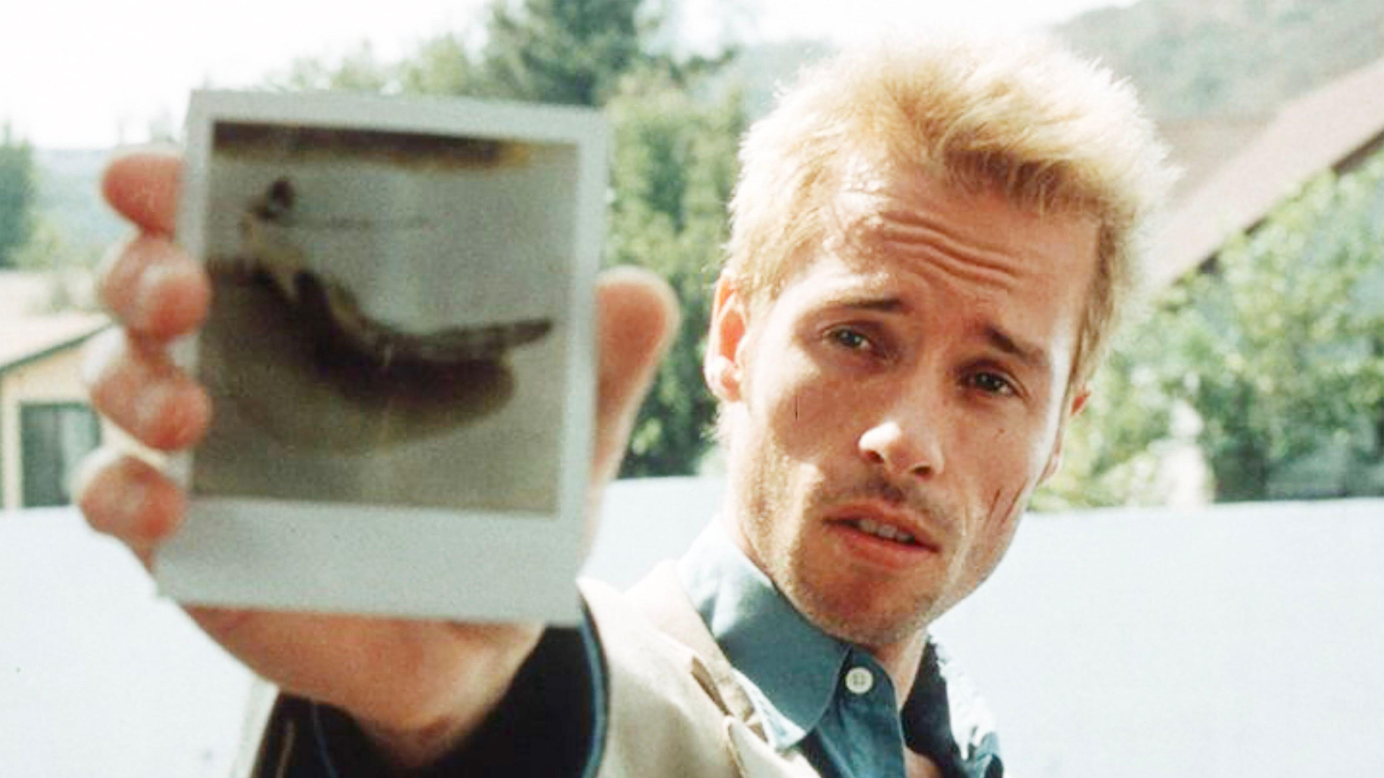 Guy Pearce como Leonard sosteniendo una foto polaroid en Memento.