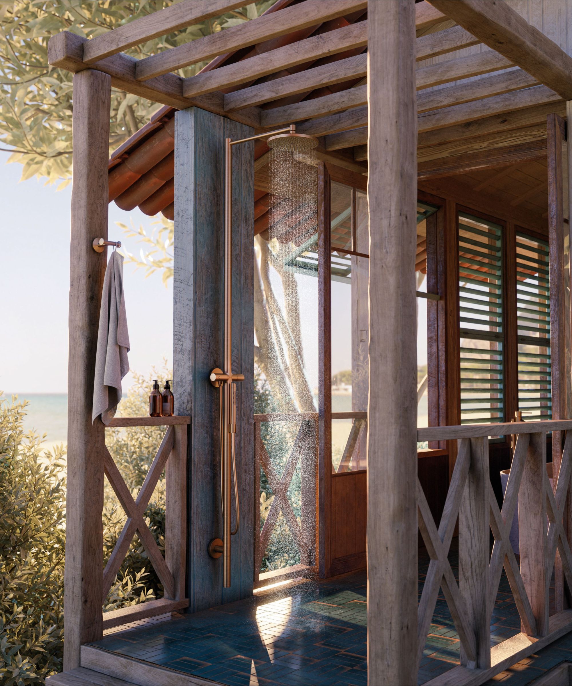 A rustic timber-framed outdoor shower enclosure with teal tiled floor, copper fittings and a glass screen, overlooking an olive tree and sea view.