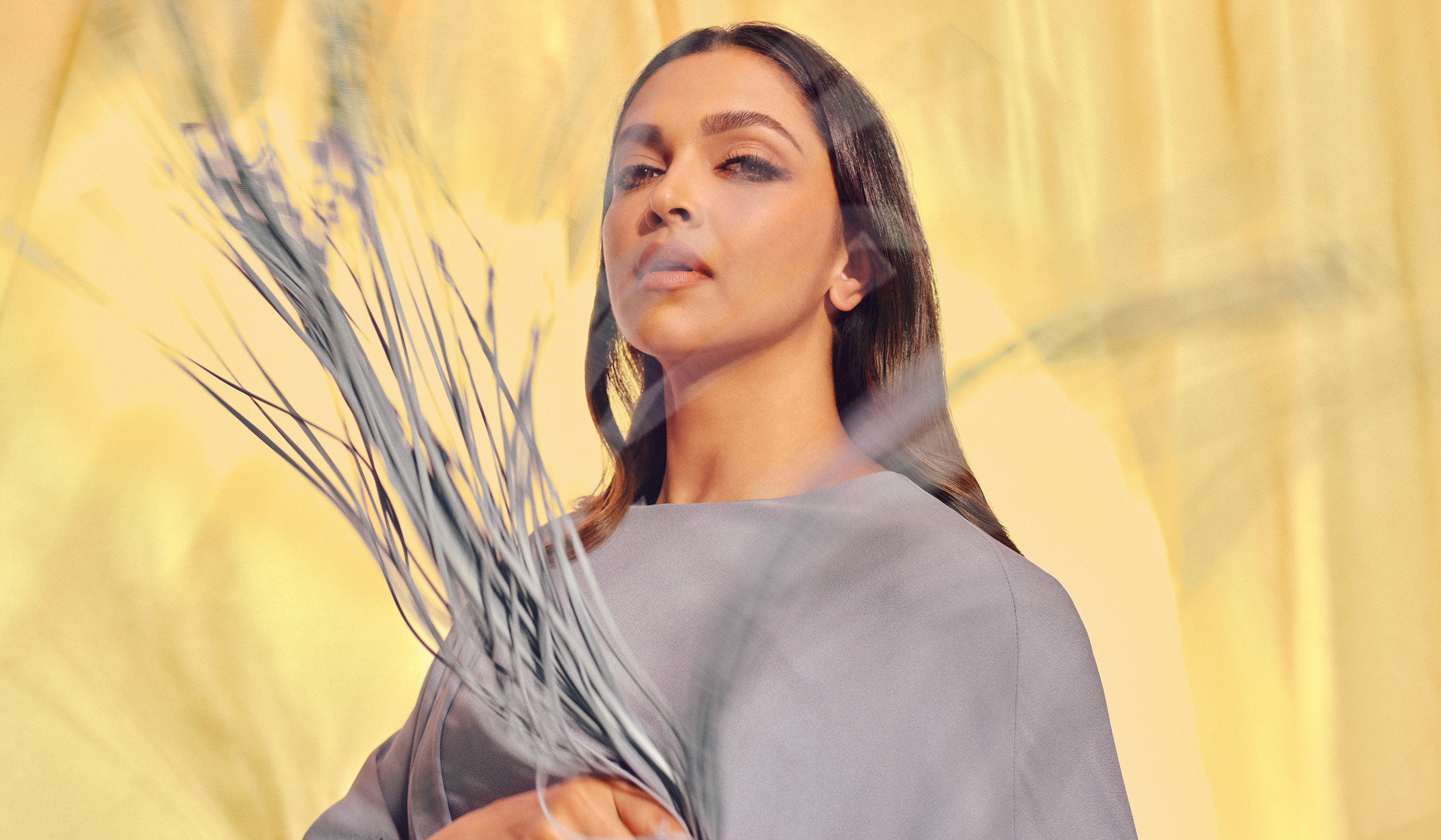 deepika padukone wearing a grey dress and holding up its fringe as it's moving
