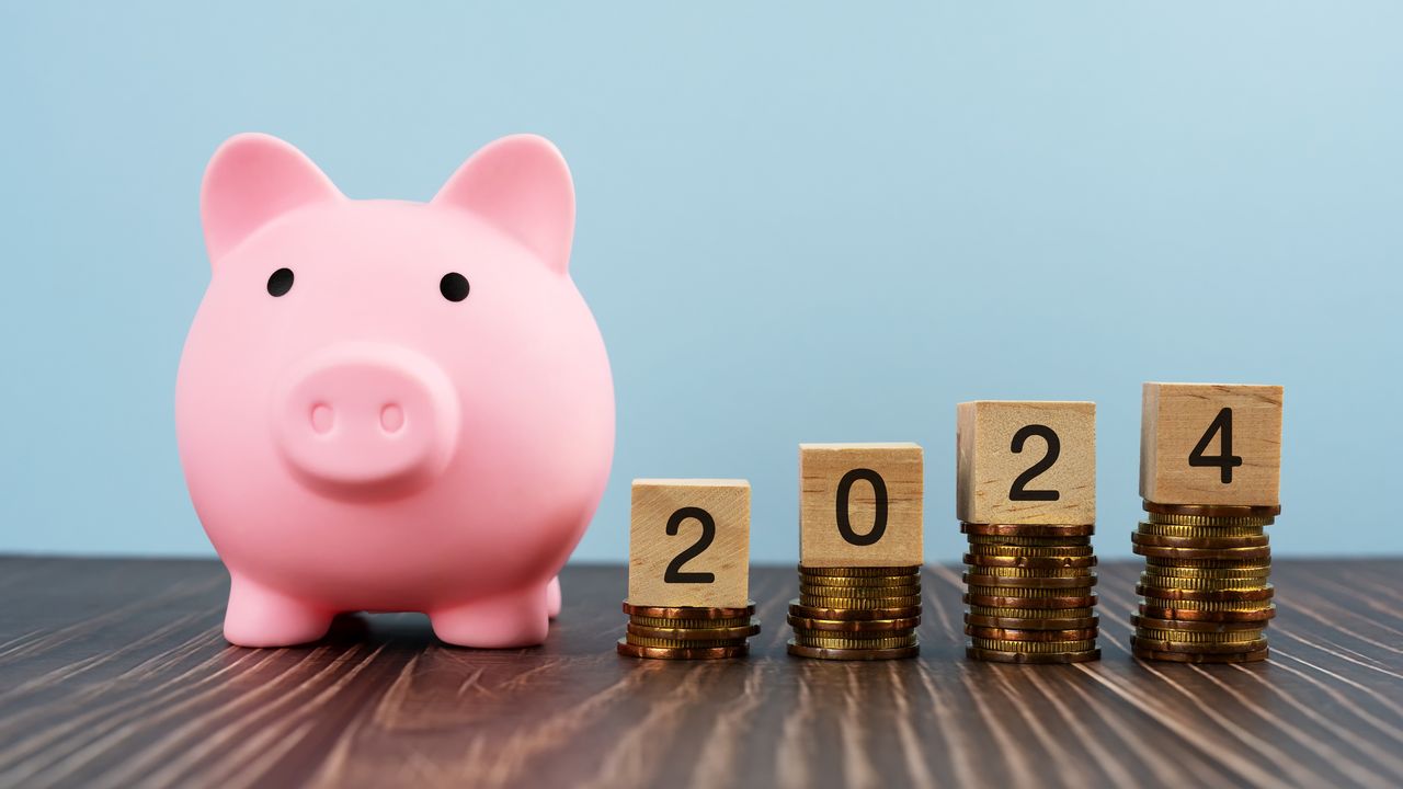 A piggy bank next to blocks that spell out 2024 on top of subsequently higher stacks of coins.