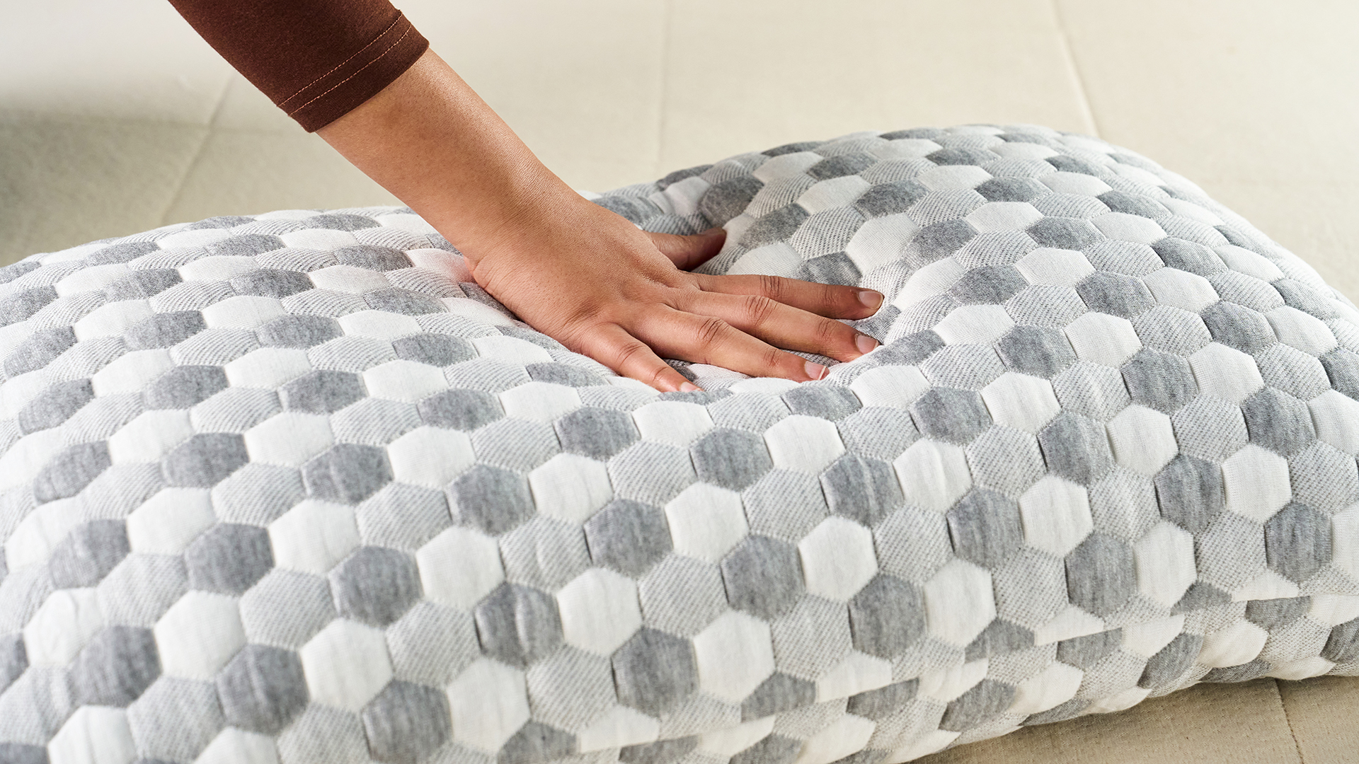 Hand pressing down on the Layla Kapok Pillow