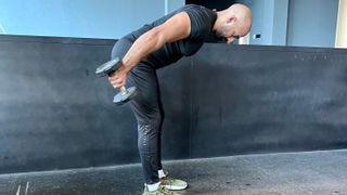 a photo of trainer Ali Malik performing a dumbbell tricep kickback