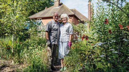 Old couple standing outside their house