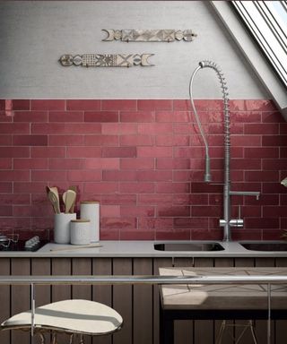Pink kitchen wall tile ideas behind a white counter and chrome faucets in a sloped kitchen.