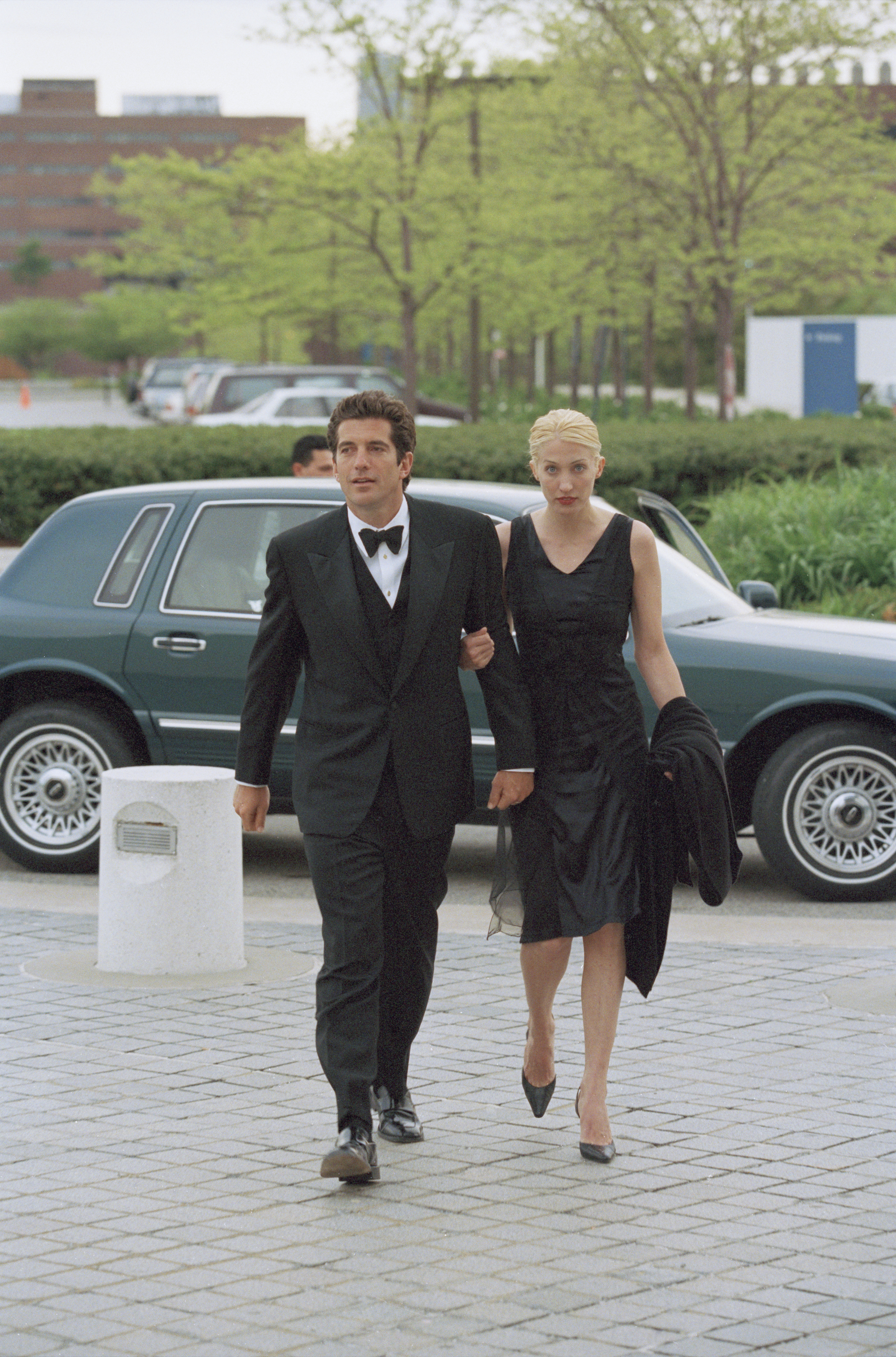 John F. Kennedy Jr. and Carolyn Bessette Kennedy walking in a tux and black dress