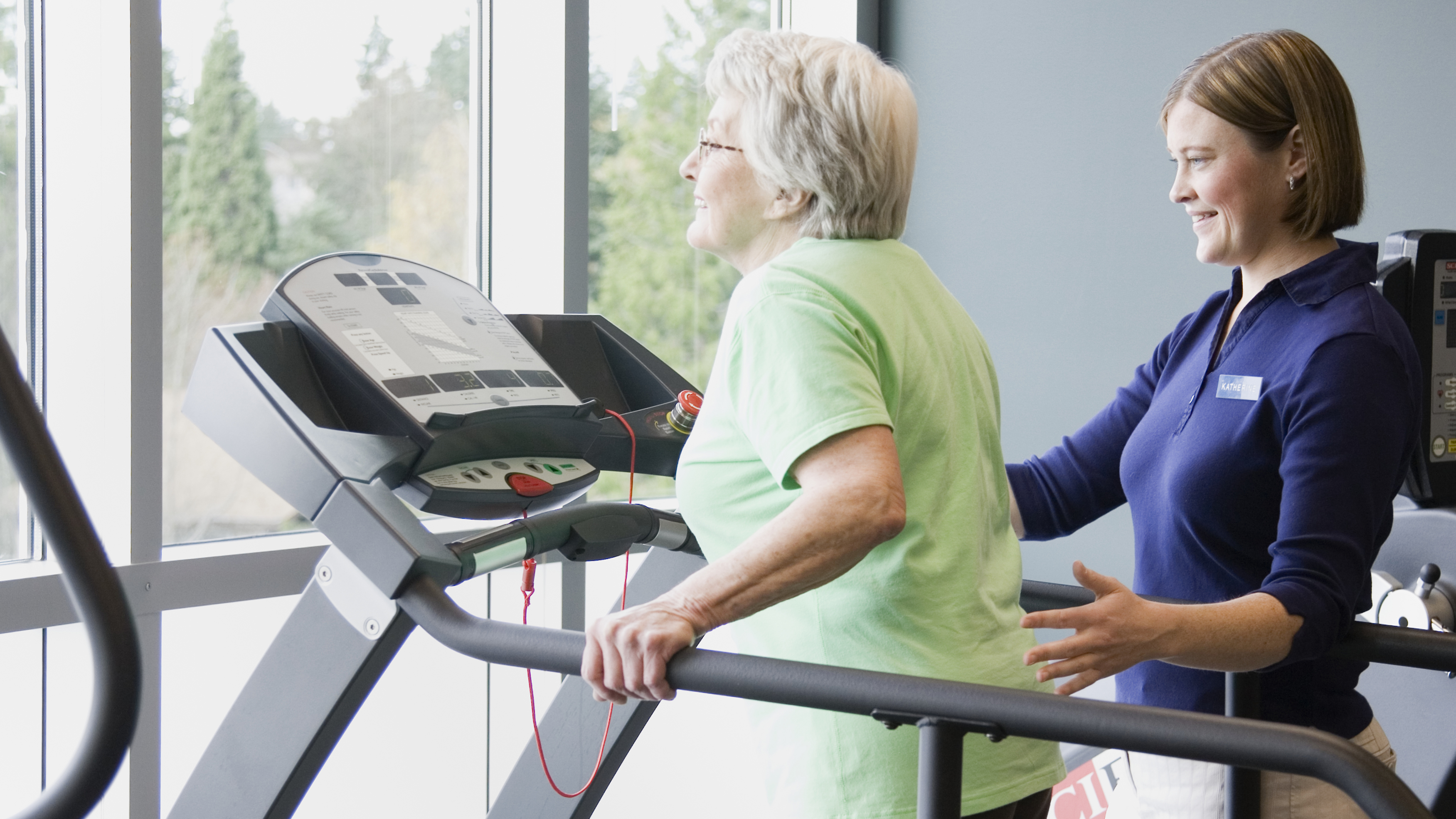 Physiotherapist helping an elderly man on a treadmill