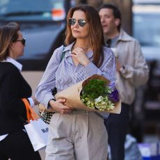 Katie Holmes wears a blue shirt with dark cream trousers.