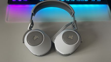 Corsair HS65 Wireless gaming headset sitting on a desk with RGB lighting